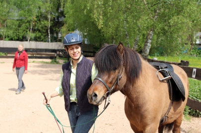Reiterin führt ihr Pferd lächelnd in der Reitbahn auf dem Gestüt Nahetal