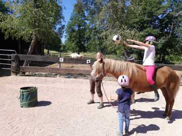 Kinder spielen mit Pferden: Ballwerfen in den Futtersack auf dem Gestüt Nahetal