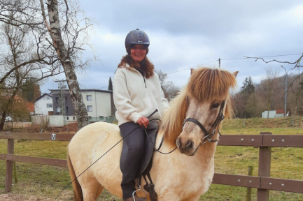 Reiterin lächelnd auf dem Pferd beim Reiten auf dem Gestüt Nahetal